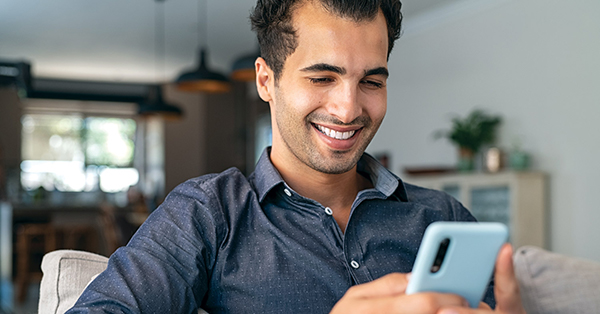 guy-at-home-couch-looking-at-mobile-phone-1500x785-2